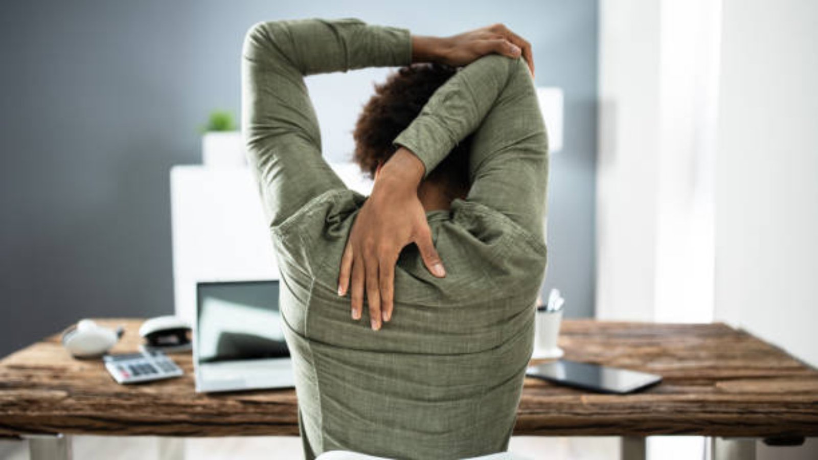 Rear View Of A Businessman Stretching His Arms In Office